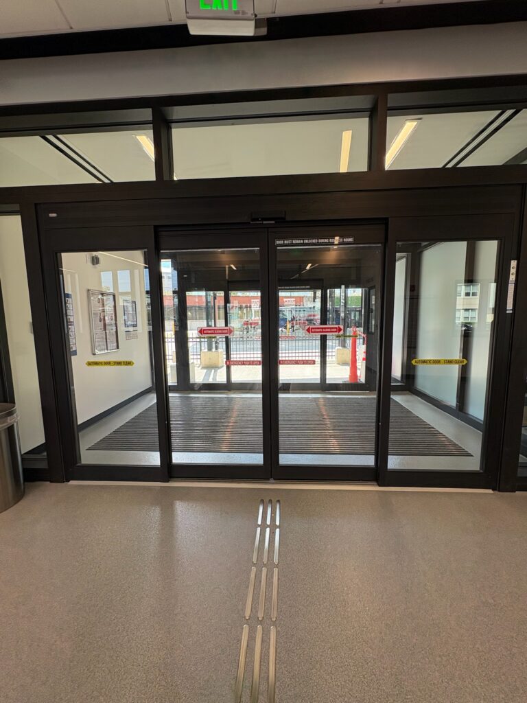 photo shows glass sliding doors, a lobby vestibule and driveway for buses.